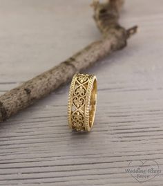 a gold ring sitting on top of a piece of wood next to a twig