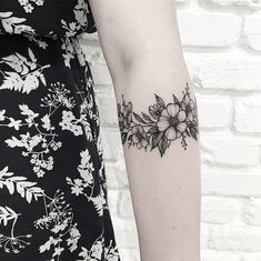 a black and white photo of a woman's arm with flowers tattooed on it