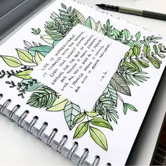 a spiral notebook with leaves and writing on the page, next to a laptop keyboard