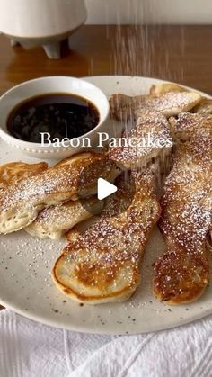 pancakes on a plate with syrup and powdered sugar being sprinkled over them