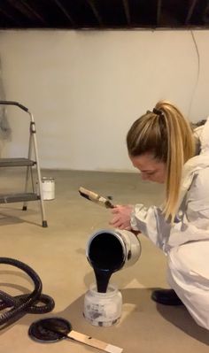 a woman in white coat pouring paint onto a bucket