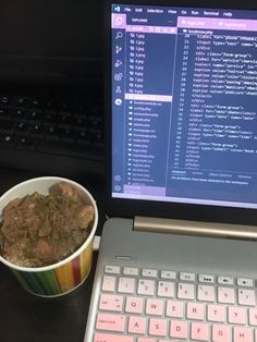 a bowl of food sitting next to a laptop on a desk with the screen turned on