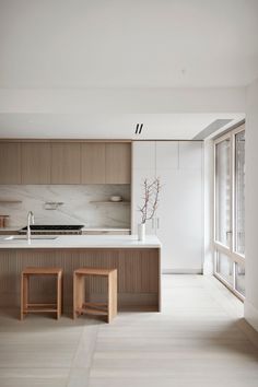 a kitchen with marble counter tops and wooden stools in front of an open window