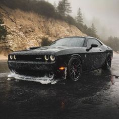 a black sports car driving down a wet road