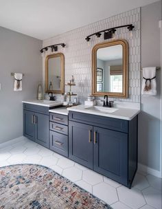 a bathroom with two sinks, mirrors and rug on the floor in front of it