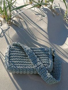 a crocheted purse laying on the sand