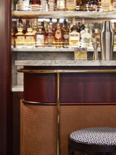 a bar with liquor bottles behind it and a stool next to it in front of the bar