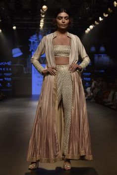 Modern, new-age and millennial, this metallic work embellished jacket is teamed up with a bustier and high waist straight raw silk pants. The jacket is accentuated with thread and pearl embroidery, along with metal work embellishments. 
Jacket with bustier and pants
Pearl and thread embroidery
Long jacket - Aza Fashions Lehenga Bollywood, Embroidered Beads, Lehenga Collection, Beige Jacket, Embellished Jacket, Bridal Lehenga Choli, Chaniya Choli, Silk Pants, Creative Wedding