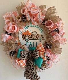 a wreath with an orange truck and leopard print bow hanging on the front of a door