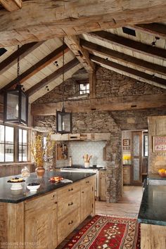 a rustic kitchen with stone walls and wooden beams, black counter tops and an island in the middle