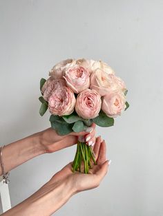 two hands holding a bouquet of pink roses