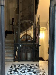 the entrance to an old building with a clock on it's wall and tiled floor