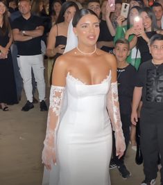 a woman in a white dress standing next to a crowd