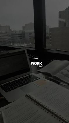 an open laptop computer sitting on top of a desk next to a book and pen