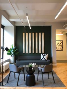 a living room filled with furniture next to a wall covered in vertical striped art pieces