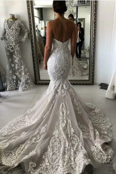 a woman in a wedding dress looking at herself in the mirror