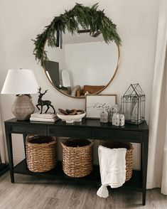 a black table with baskets under a round mirror