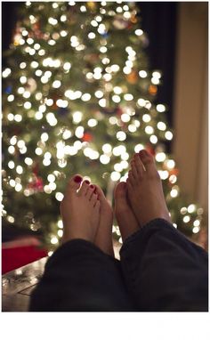 a person with their feet up in front of a christmas tree