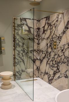 a bathroom with marbled walls and flooring next to a walk in shower stall