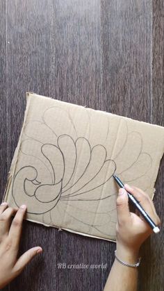 someone is drawing on a piece of cardboard