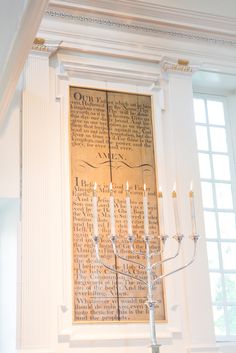 a tall candelabra with candles on it in front of a large poster