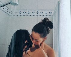 a woman is standing in the shower and touching her face