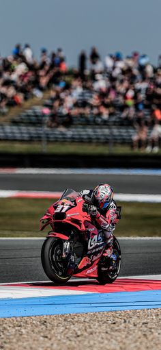 a person riding a motorcycle on a race track in front of a crowd of people