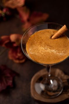 a drink in a glass with a cinnamon stick sticking out of the top on a table