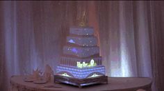 a wedding cake is lit up with blue lights and stars on the ceiling behind it