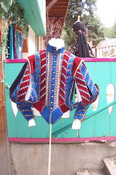 a blue and red jacket on display in front of a green wall with other items