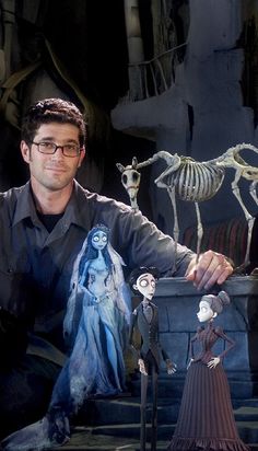 a man sitting in front of some fake skeletons