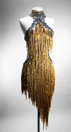 a mannequin with gold and blue beads on it's neck, standing in front of a gray background