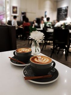 two cups of cappuccino sit on a table