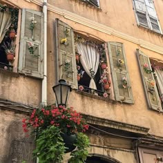 an old building with shutters and flowers on the windows