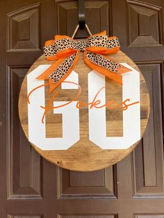 a door hanger with an orange ribbon and leopard print bow on it that says go