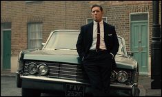 a man in a suit standing next to a car