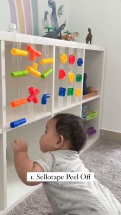 a small child playing with toys in a playroom on carpeted floor next to bookshelf