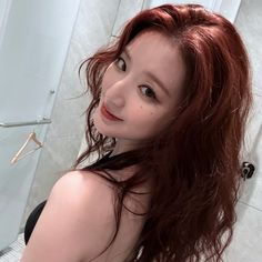 a woman with long red hair standing in front of a shower