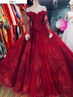 a red ball gown with long sleeves on display in front of mannequins