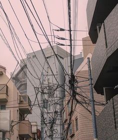 many wires are tangled to the side of buildings in an urban area with tall buildings behind them