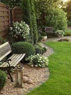 a wooden bench sitting in the middle of a lush green yard next to a stone path