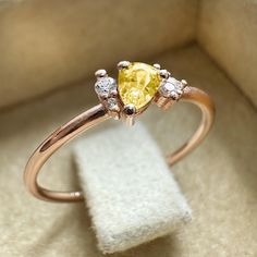 a yellow diamond ring sitting on top of a white cloth