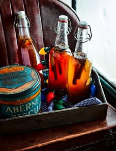 three bottles of alcohol sitting on top of a wooden box next to a canister