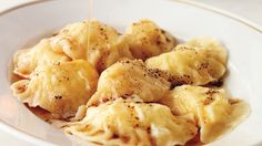 a white bowl filled with dumplings covered in seasoning on top of a table