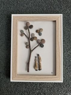 some rocks and a tree in a frame on the floor next to a gray carpet