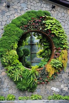 a round window covered in green plants next to a stone wall