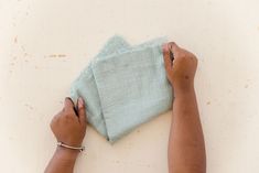 a person wiping up a cloth on top of a white wall with two hands holding it