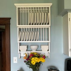 a vase filled with yellow flowers sitting on top of a counter next to plates and cups