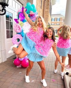 two women in pink and blue outfits are posing for the camera while holding up balloons