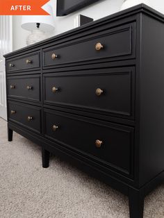 a black dresser with gold knobs in a white room next to a large mirror